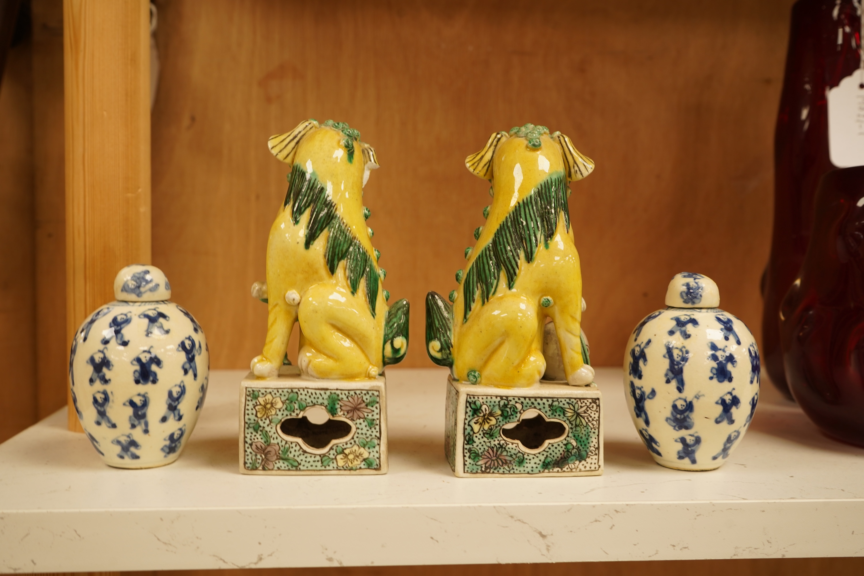 A pair of late 19th/early 20th century Chinese famille verte lion dogs and a similar pair of blue and white miniature ‘boys’ jars and covers, 15cm